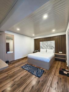 a bedroom with a large white bed and wooden floors at Pineview Escapes in Jālāpahār