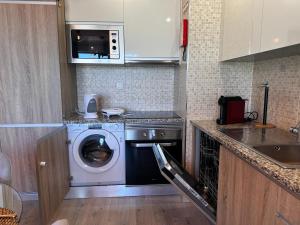 a kitchen with a washing machine and a microwave at Elite 7E - Vistas Mar na Praia da Rocha in Portimão