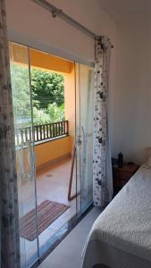 una camera da letto con porta a vetri che conduce a un balcone di Aratuba, Itaparica BA, Cond enclosed, 3 min beach a Vera Cruz de Itaparica