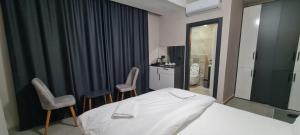 a bedroom with a bed and two chairs and a bathroom at Mersin Panorama Otel in Kargipınarı