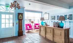 a room with a desk with a clock and pink chairs at The Brewer's House in Southwold