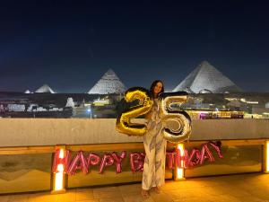 カイロにあるPyramids Top view innの風船を持って棚の上に立っている女性