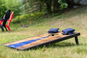 a wooden surfboard sitting in the grass next to a chair at 70 Private Acres-Sleeps 12-Fire Pit-Pet Friendly in Conway