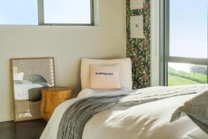 a bedroom with a bed and a mirror and a chair at The Kina Cottage in Tutukaka