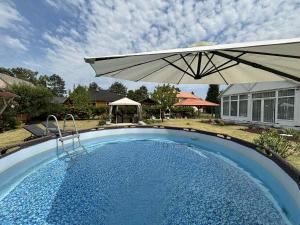 a large pool with an umbrella and a house at Tündér-Lak Apartman in Balatonmáriafürdő