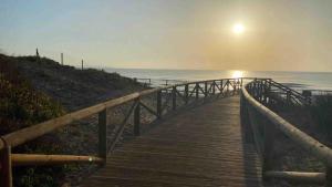 a wooden boardwalk leading to the ocean at sunset at Villa Margarita, Guardamar Del Segura in Guardamar del Segura