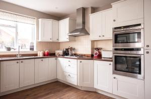 a kitchen with white cabinets and stainless steel appliances at The Brewer's House in Southwold