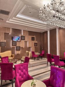 a waiting room with red chairs and tables and a chandelier at Properti Sun Premira Condotel Apartment Adi Sucipto Yogyakarta in Demangan