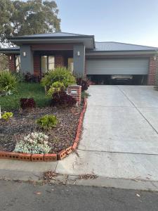 a house with a driveway with flowers in front of it at New House in Beaufort in Beaufort