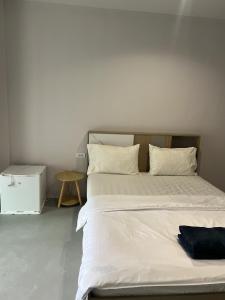 a bed with white sheets and a black bag on it at Hongheng Beach Residence - Walk to Jomtien & Night Market ! in Jomtien Beach
