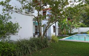 une maison avec un arbre à côté d'une piscine dans l'établissement Harris Villa, à Hikkaduwa