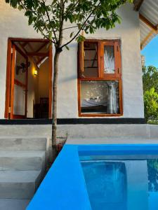 a house with a swimming pool next to a tree at Kurundu House Mirissa in Mirissa