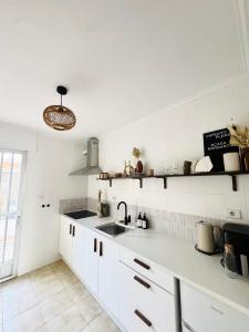 a kitchen with white cabinets and a sink and a window at Casa Margarita in San Pedro del Pinatar