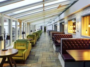 a waiting room with couches and tables and chairs at Mercure Haydock Hotel in Haydock