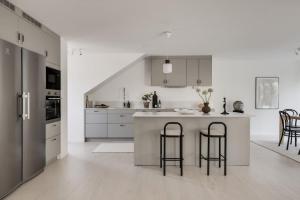 Newly built Scandinavian villa in Gothenburg في Hällsvik: مطبخ أبيض مع جزيرة كبيرة مع كرسيين للحانة