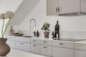 Newly built Scandinavian villa in Gothenburg في Hällsvik: مطبخ أبيض مع دواليب بيضاء ومغسلة