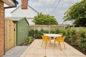 a patio with a table and chairs and a fence at The Beach House in Overstrand