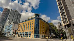 a yellow building on a city street with tall buildings at Holiday Inn Express London Stratford by IHG in London