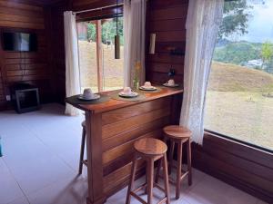 a bar in a room with two stools and a window at Sítio Martinelli, Caravaggio in Santa Teresa