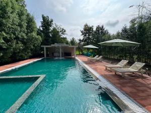 a swimming pool with two chairs and an umbrella at The Forest Chapter by Sayaji Madhai in Sohāgpur