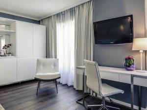 a room with a desk and two chairs and a tv at Mercure Hotel Raphael Wien in Vienna
