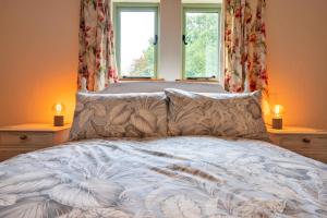 a bedroom with a bed with two windows at Finest Retreats - Rough Close Farm Cottage in Ashover