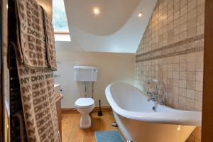a bathroom with a tub and a toilet at Finest Retreats - Rough Close Farm Cottage in Ashover +21 photos