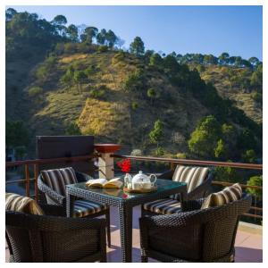 een tafel en stoelen op een balkon met een berg bij Sanskari Nivas family holiday home in Kasauli +8 foto's