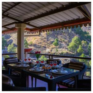 een tafel met wijnglazen op een balkon met uitzicht bij Sanskari Nivas family holiday home in Kasauli