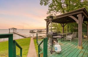 a wooden deck with a grill and a table on the water at Charming 4BR Lakefront Getaway in Tool