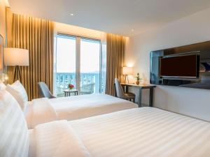 a hotel room with two beds and a flat screen tv at Novotel Phuket City Phokeethra in Phuket Town