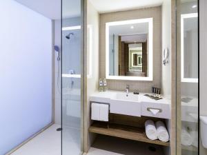 a bathroom with a sink and a mirror and a shower at Novotel Phuket City Phokeethra in Phuket Town