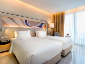 two beds in a hotel room with white sheets at Novotel Phuket City Phokeethra in Phuket Town