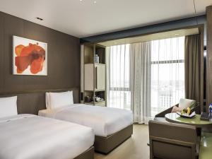 a hotel room with two beds and a desk at Novotel Shanghai Clover in Shanghai