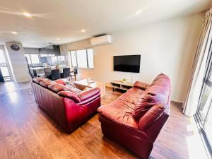 a living room with two leather couches and a tv at Modern Family Retreat Near Auckland City & Airport in Auckland