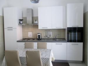 a kitchen with white cabinets and a table with chairs at Vacanza alla Chiesa Diruta in Grottole