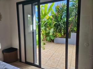 an open glass door with a patio with plants at Studio Belle Place in Le Gosier