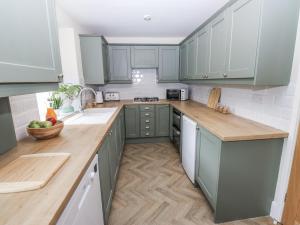 a kitchen with green cabinets and wooden counter tops at Court Street Cottage in Saddleworth