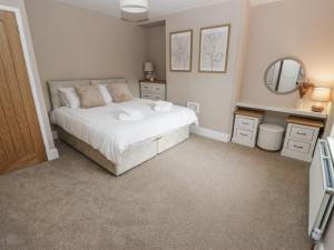a bedroom with a white bed and a mirror at Court Street Cottage in Saddleworth