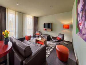 a living room with a leather couch and orange chairs at Clarion Congress Hotel Bratislava in Bratislava