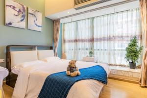 広州市にあるXuanzhi Hotelの寝室のベッドの上に座っているテディベア