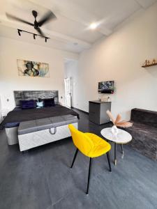 a bedroom with a large bed and a yellow chair at Casa Oceanus - 3 Bedroom - Sea Facing Pool Villa - Ganpatipule in Ganpatipule