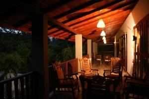 a porch with chairs and tables and a wooden ceiling at Hikka Resort in Hikkaduwa