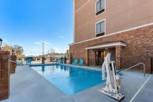 a swimming pool with chairs and a building at Comfort Inn & Suites Augusta West Near Fort Gordon in Augusta