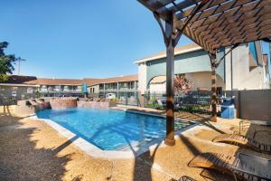 a swimming pool with chairs and an umbrella at Quality Inn Near Lake Marble Falls in Marble Falls