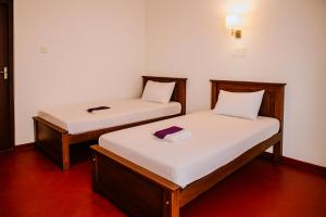 two beds in a room with white sheets at Premier Stay in Chavakachcheri