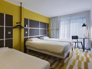 a hotel room with two beds and a desk at ibis Styles Massy Opéra in Massy +54 photos