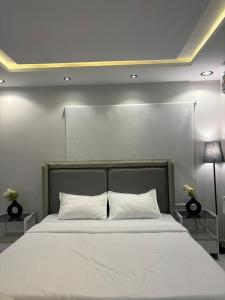 Un dormitorio con una gran cama blanca con dos mesas. en #3 Daily Rental Studio in Sulaymaniyah, en Riad