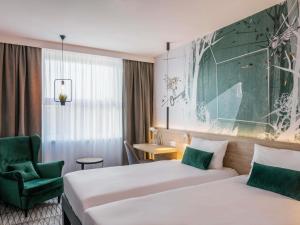 a hotel room with two beds and a chair at ibis Styles Kraków East in Kraków