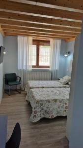 a bedroom with two beds and a chair and a window at La Posada De Faustina in Naveda